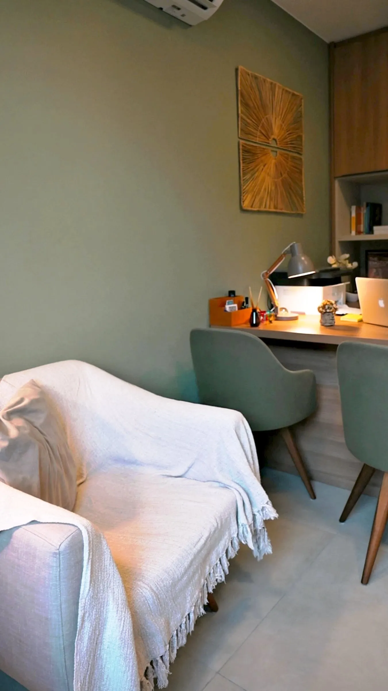 Mesa de atendimento com cadeiras verdes e um quadro na parede
